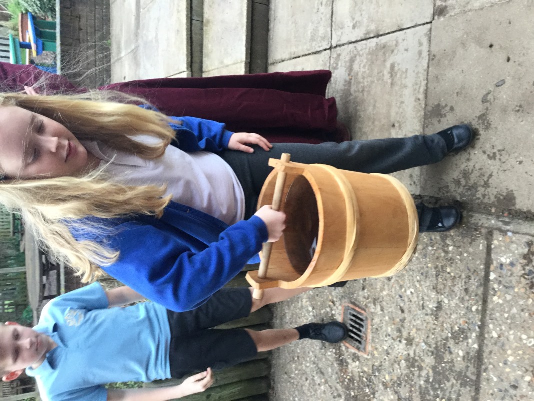 Student carrying medieval bucket full of water