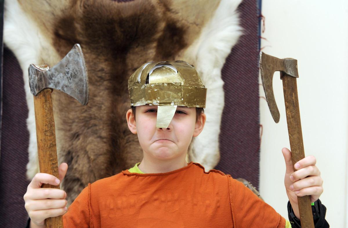 A boy holding up replica Viking axes at a Marvellous History workshop