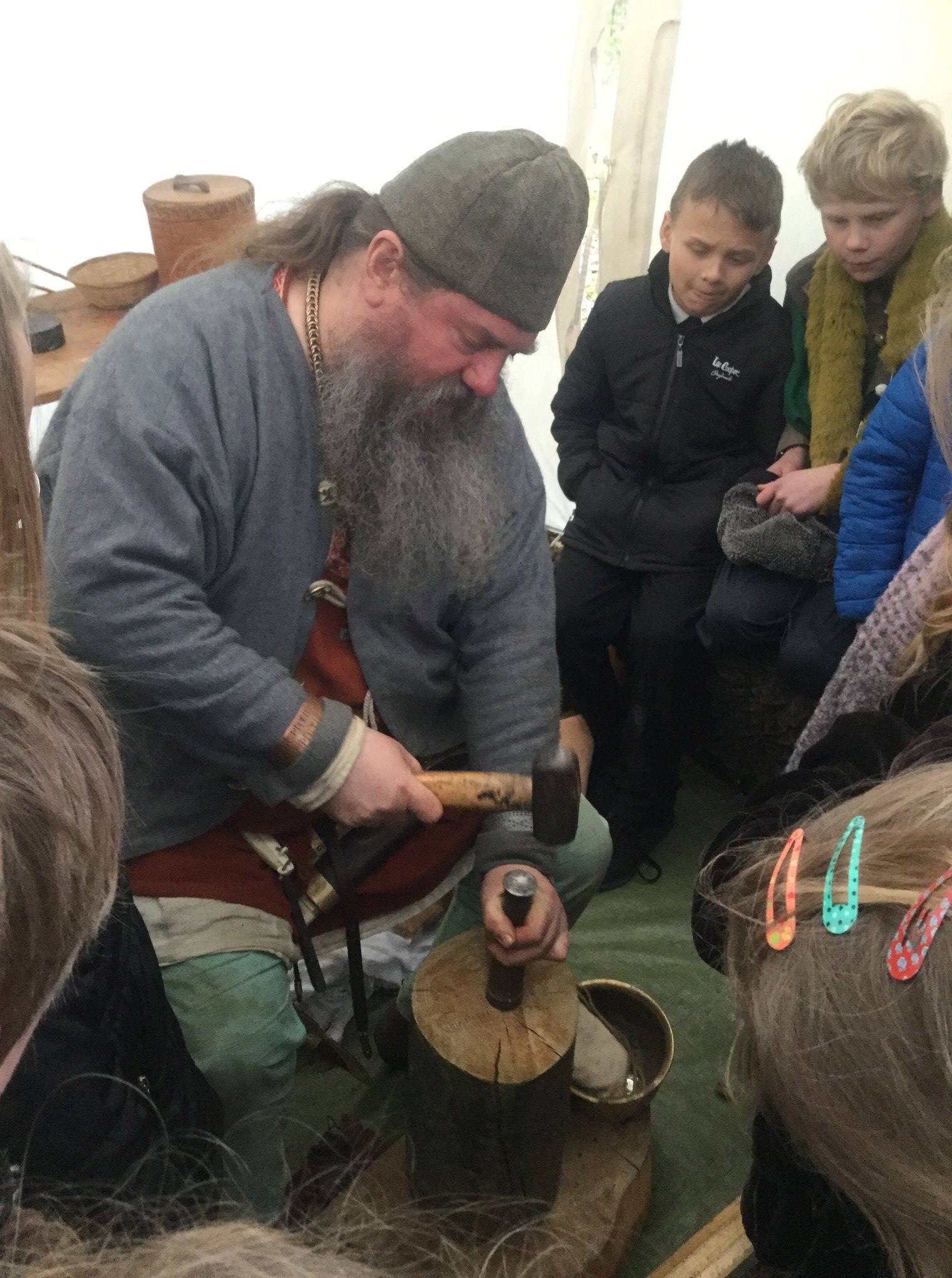 A Viking showing children how to strike coins at a workshop from Marvellous History